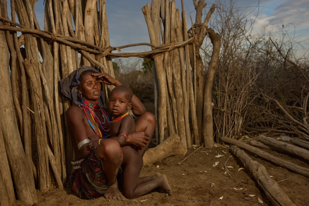 Arbore woman holding child among wooden fence structures in southern Ethiopia | Michaela Pupíková Photography