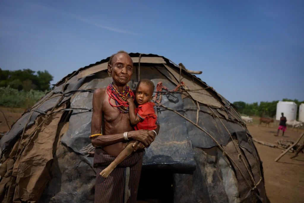 Dassanech woman holding child in front of dome-shaped hut in Ethiopian village | Michaela Pupíková Photography