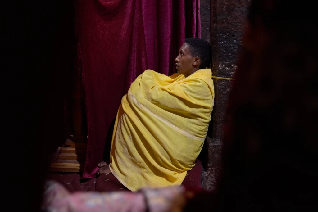Solitary monk meditating inside a narrow stone-hewn chamber in Lalibela church | Michaela Pupíková Photography