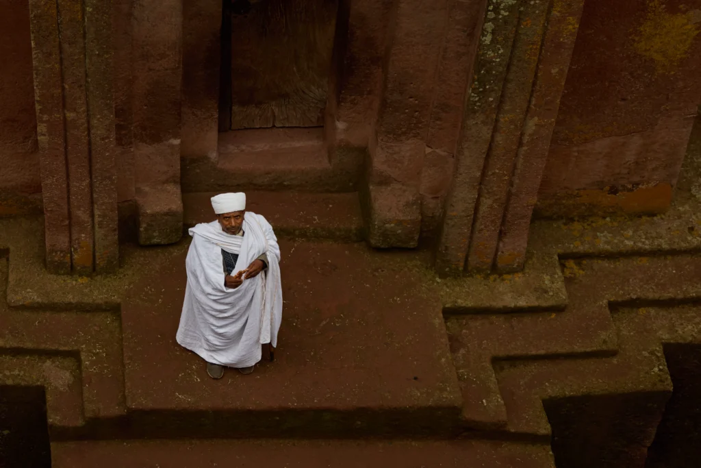 Ethiopian Orthodox monk standing in stone-carved church doorway in Lalibela | Michaela Pupíková Photography