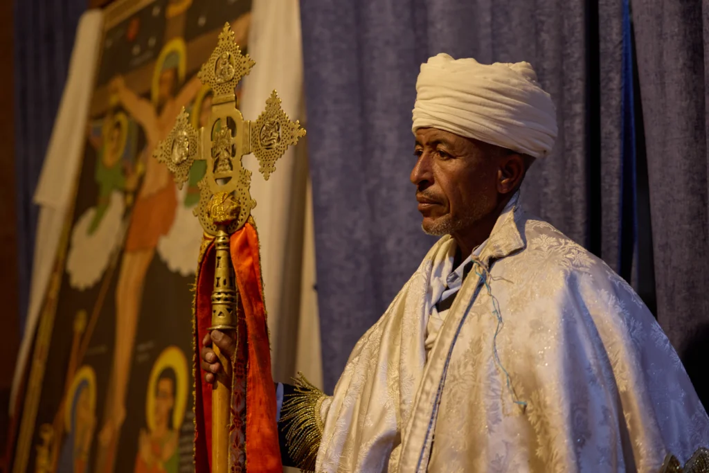 Side portrait of Ethiopian monk holding a traditional hand cross in Lalibela | Michaela Pupíková Photography