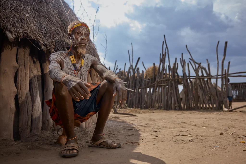 Elder Nyangatom man sitting quietly at thatched hut doorway in tribal Ethiopia | Michaela Pupíková Photography