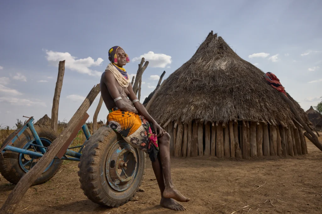 Nyangatom woman sitting on plough wheel in Nyangatom village in Ethiopia | Michaela Pupíková Photography