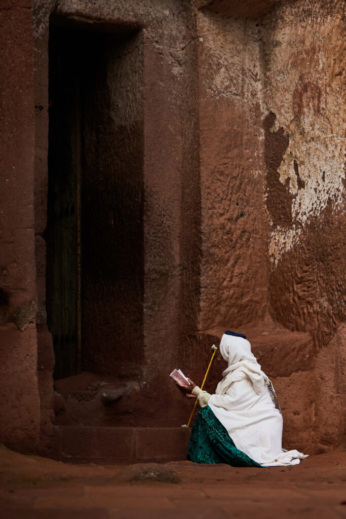 Pilgrim silhouette standing before narrow slit of light in stone corridor | Michaela Pupíková Photography